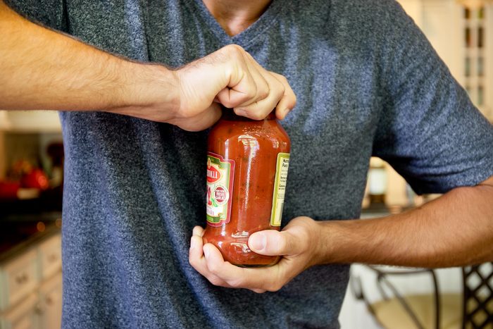 man trying to open a stubborn jar of sauce