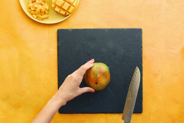 about to cut a mango on a slate cutting board