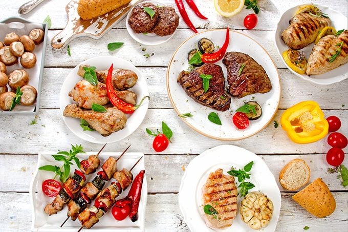 Assorted grilled meats and vegetables on a white wooden table