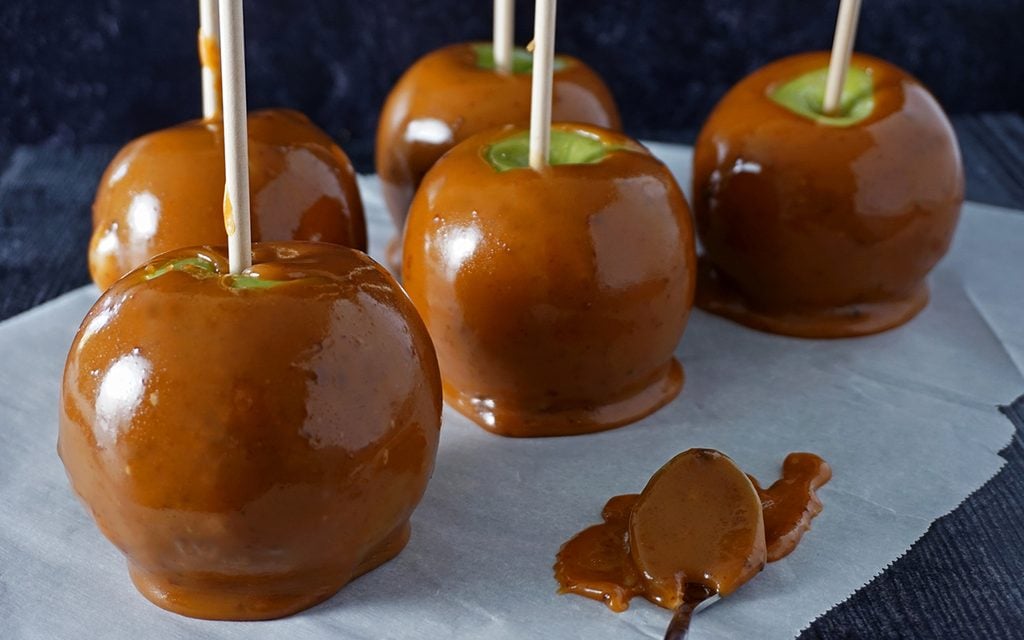 Freshly made homemade caramel apples cooling on parchment paper