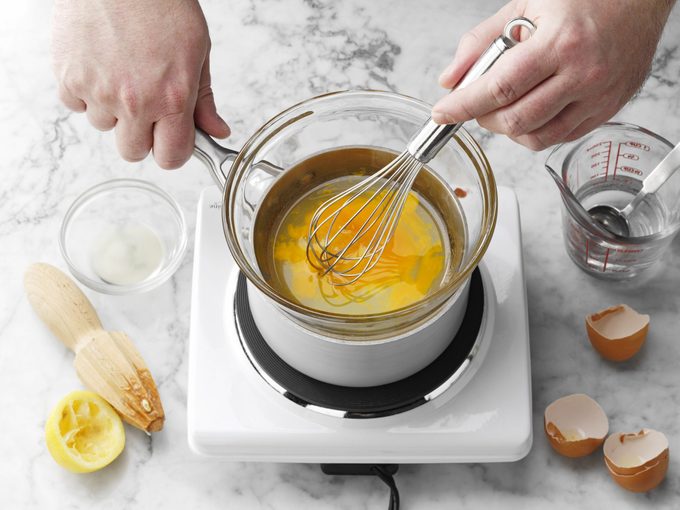 double boiler with egg and hands with whisk