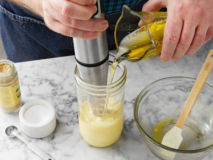 person blends olive oil with egg in a mason jar