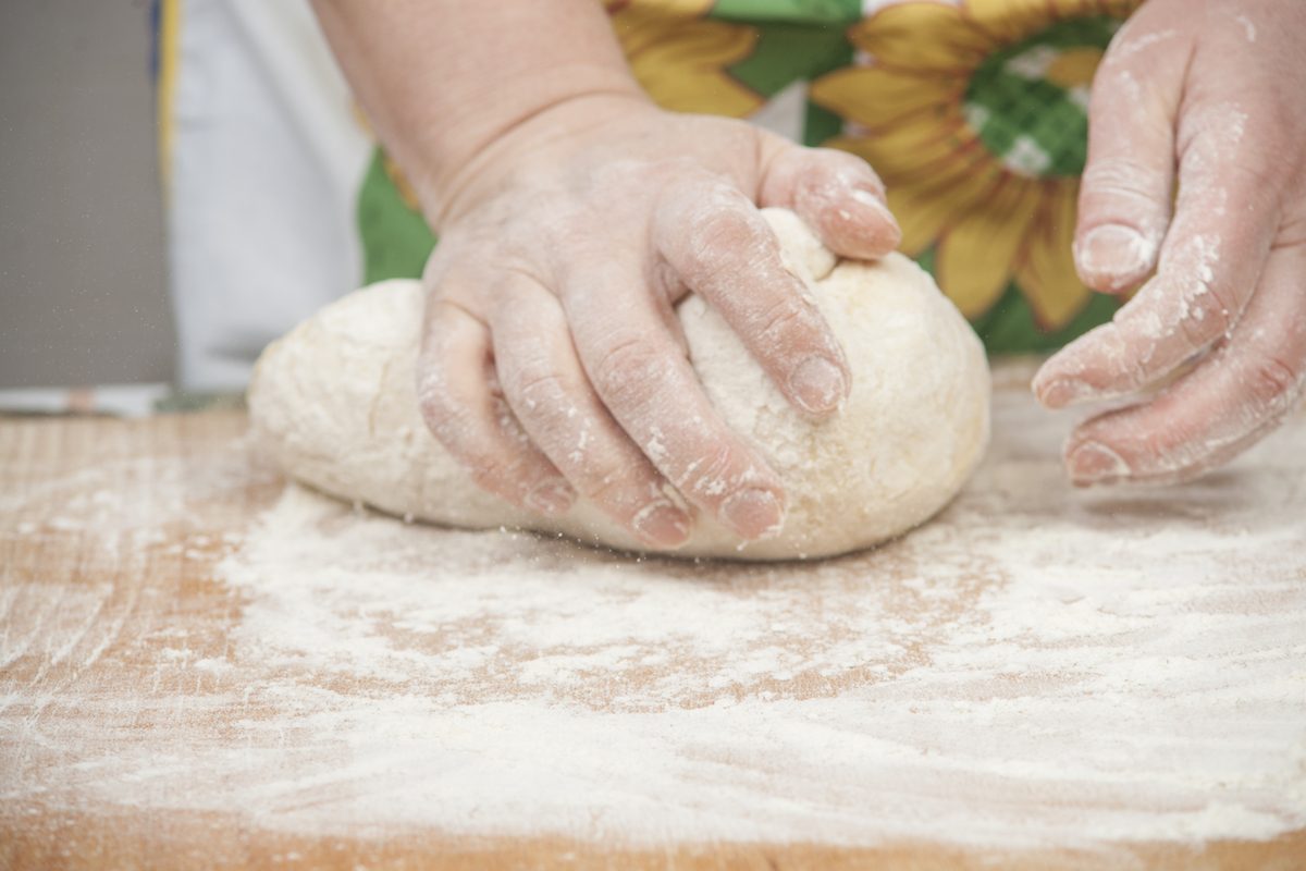 Woman's hands preparing fresh yeast dough on wooden table