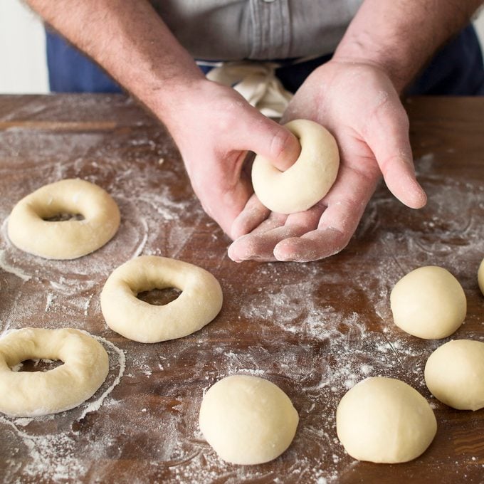 A person shaping dough into rings to make homemade bagels.
