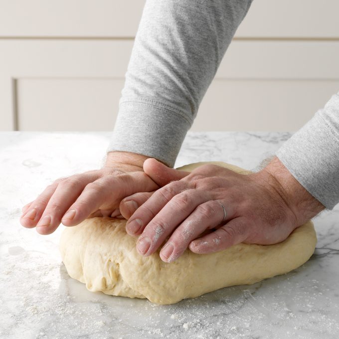 A person kneading dough to make homemade bagels.