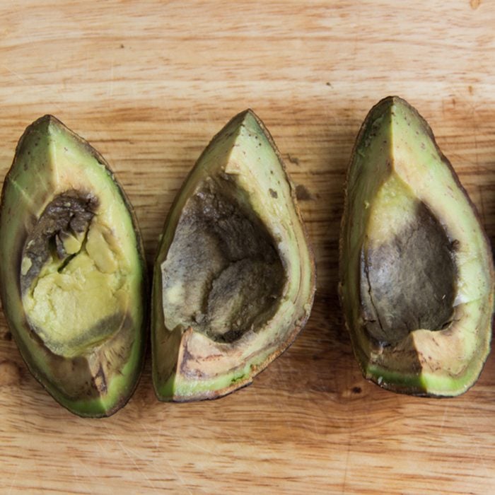 Four pieces of rotten avocado on wooden background top view; Shutterstock ID 1051896014