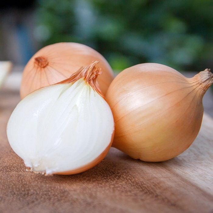 onion and onion slices on wooden cutting board.; Shutterstock ID 614533241