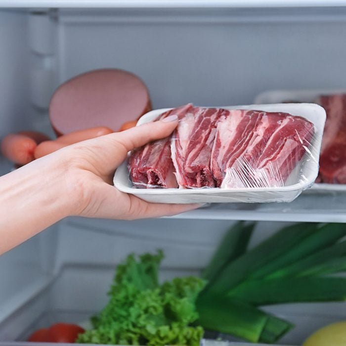 Woman putting raw meat in refrigerator, closeup; Shutterstock ID 795124657