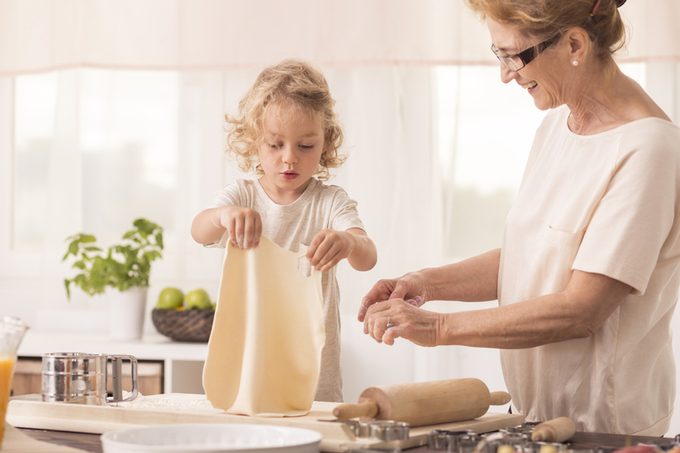 Bright kitchen interior with child making the cake with her smiling grandma