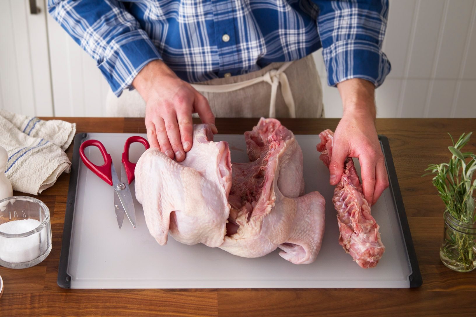 Person placing the severed backbone from the turkey off to the side if their cutting board