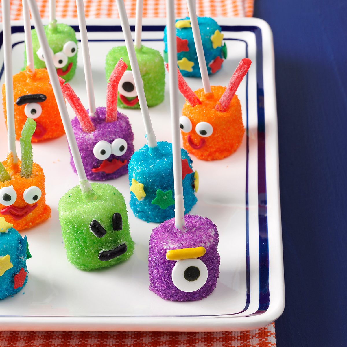 Marshmallows attached to lollipop sticks decorated as martians arranged on a plate.
