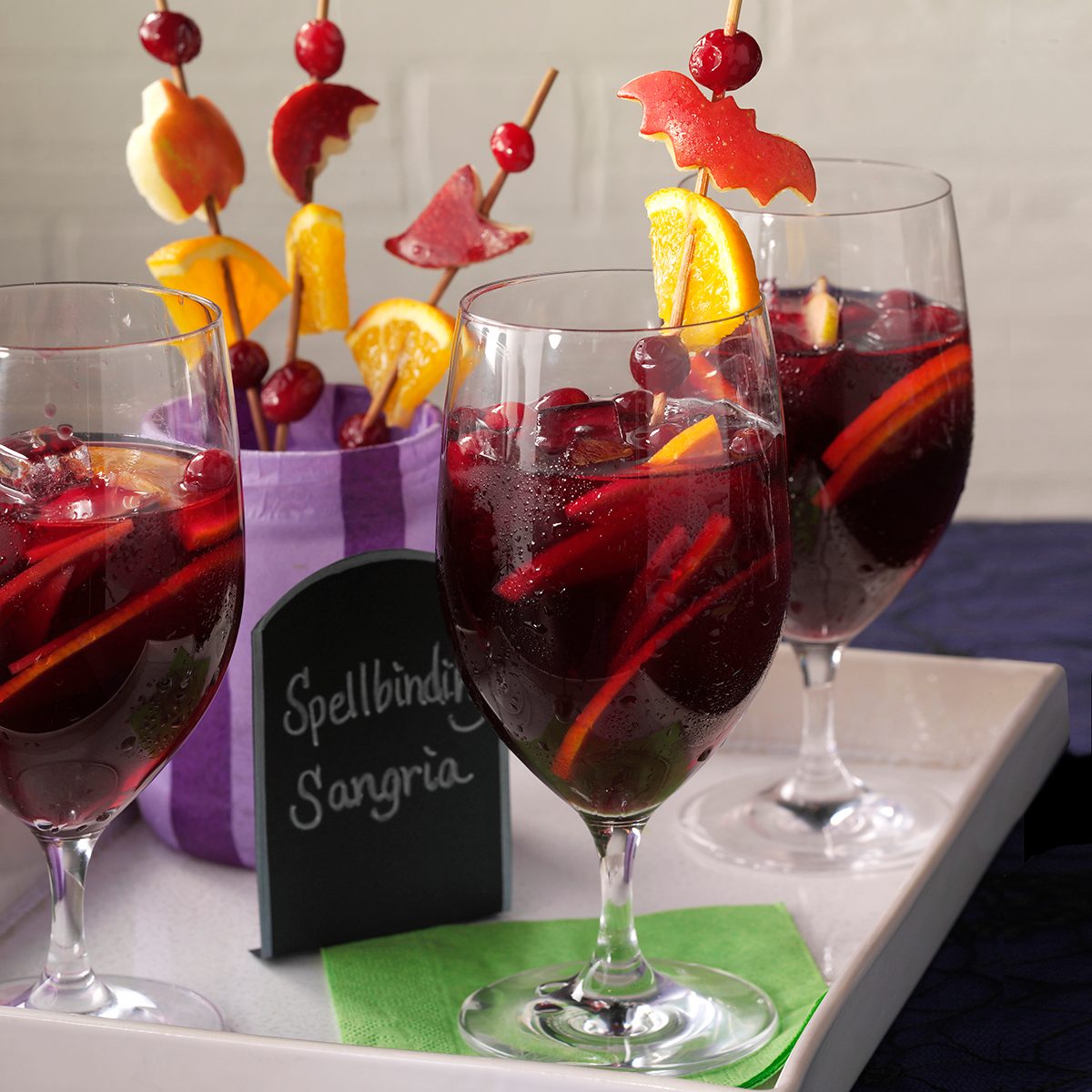 Three sangrias with fruit shaped like bats and pumpkins skewered and stuck inside