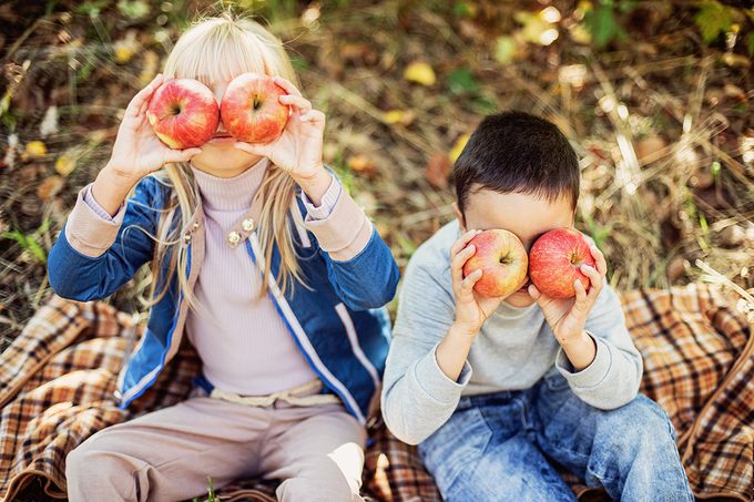Children with Apple in Apple Orchard