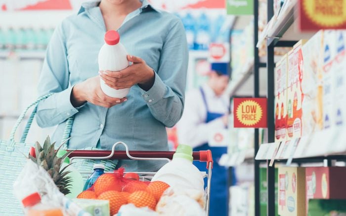 Woman doing grocery shopping at the supermarket and reading food labels, nutrition and quality concept