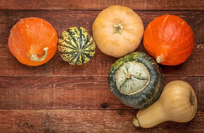 A variety of winter squash fruits on a rustic wooden table
