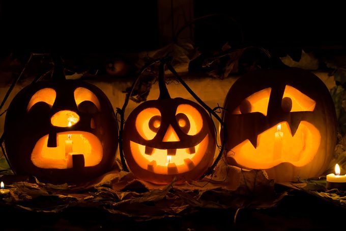 Photo composition from three pumpkins on Halloween. Crying, mad and afraid of some pumpkin against an old window, leaves and candles.