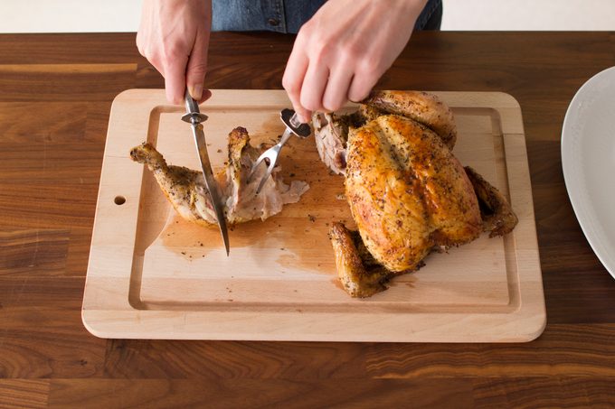 Person focusing their knife and fork on the chicken leg they removed