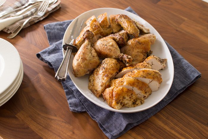 Sliced and cooked chicken on a white plate over a blue towel