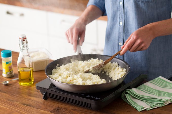 The cauliflower rice has hit the stovetop and is steaming deliciously as the cook stirs it with a wooden spoon
