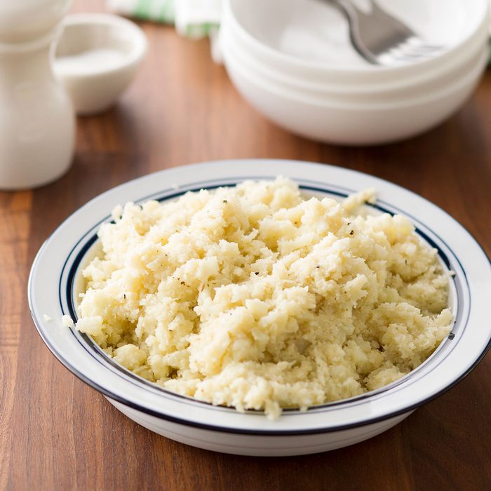 Full bowl of cauliflower rice sitting on a wood table