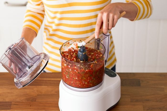 Person stirring salsa inside their blender with a spatula