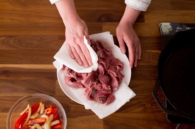 Sliced meat on a bed of paper towel being patted down