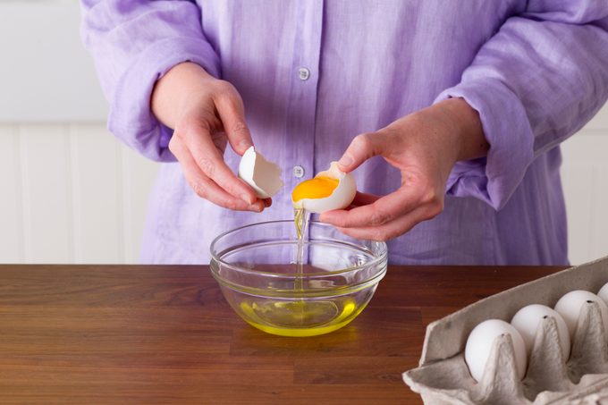 Person carefully using the egg's own shell to separate the yolk from the whites
