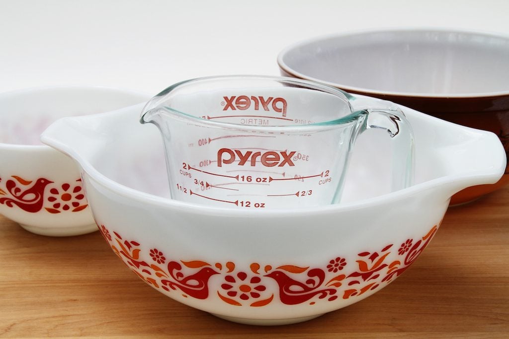 A PYREX clear glass measuring cup with several vintage Pyrex bowls. The white bowls feature the friendship design. Pyrex recently celebrated its 100th anniversary since it was introduced by Corning in 1915. The brand is now produced by World Kitchen LLC, a Corning spinoff.