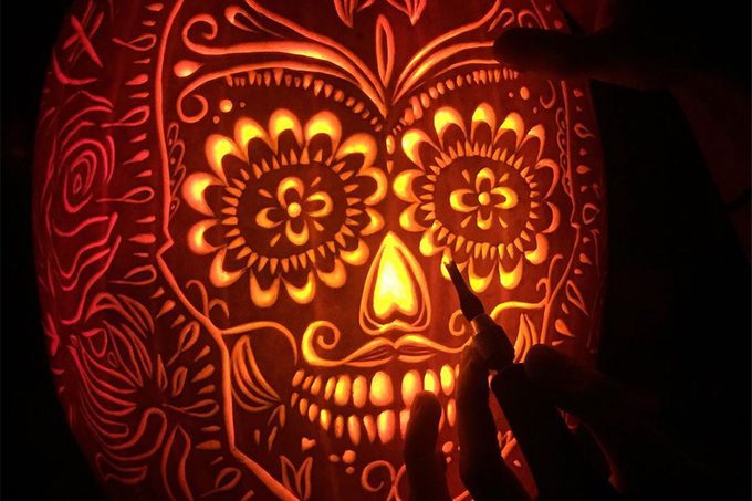 Intricately carved Day of the Dead skull on a pumpkin