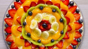 Summer dessert pizza with rows of different sliced fruit