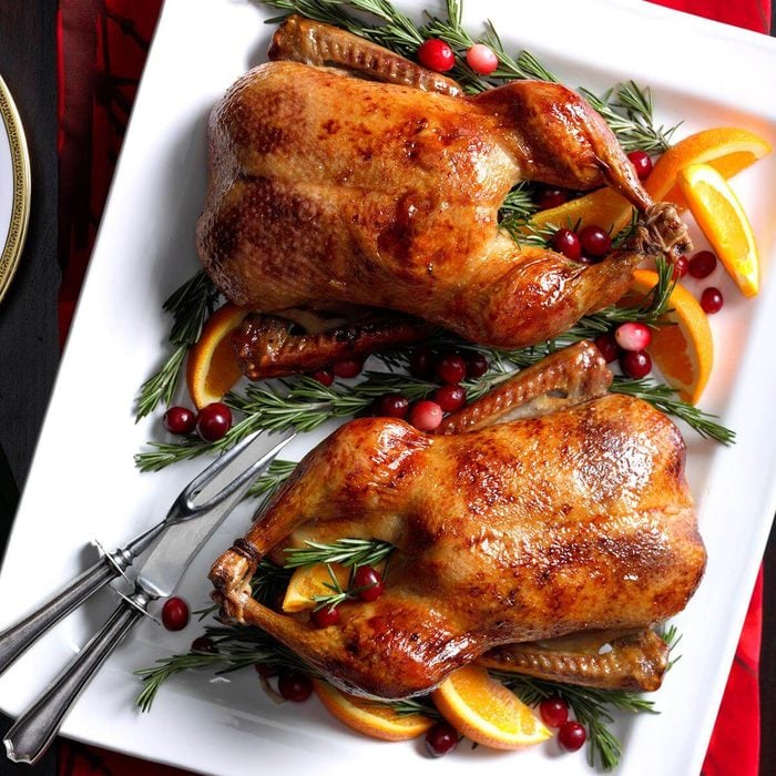 full roasted chicken served in white plate with some cranberries
