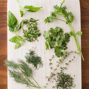 Chopped herbs spread out over a white cutting board