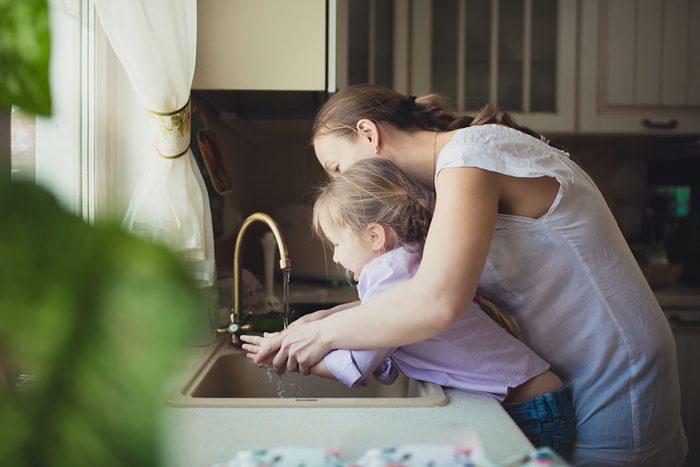 Daughter with her mother to wash their hands in the kitchen sink