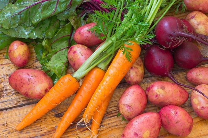 Fresh vegetables (carrots, beets, potatoes) on a wooden surface