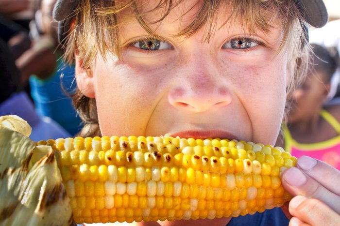 Happy boy eating corn on the cob