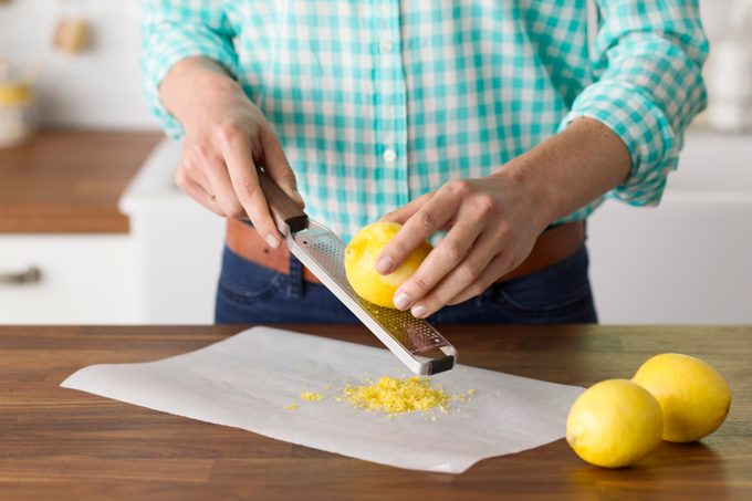 Person using a microplane to zest a lemon