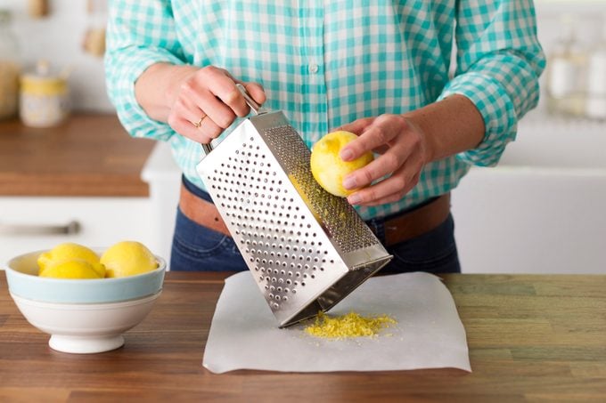 Person holding a lemon up against a grater
