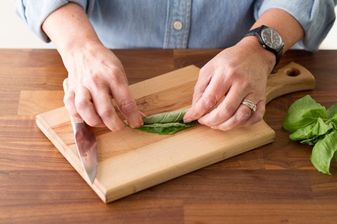 Person rolling the stack of basil leaves together