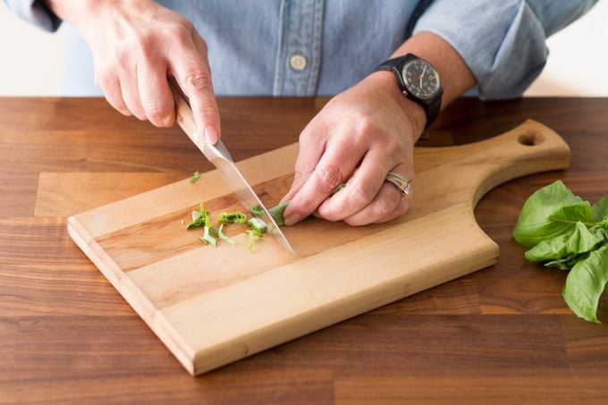 Person slicing their rolled basil into thin strips