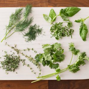 Chopped herbs spread out over a white cutting board