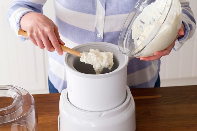 Person scooping their yogurt mix into an ice cream maker
