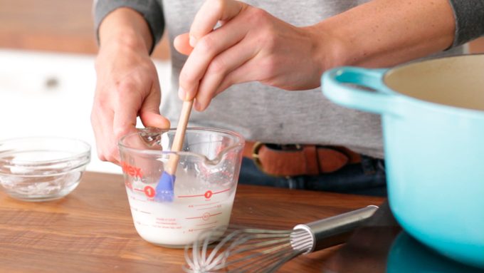 Person stirring milk in a measuring cup