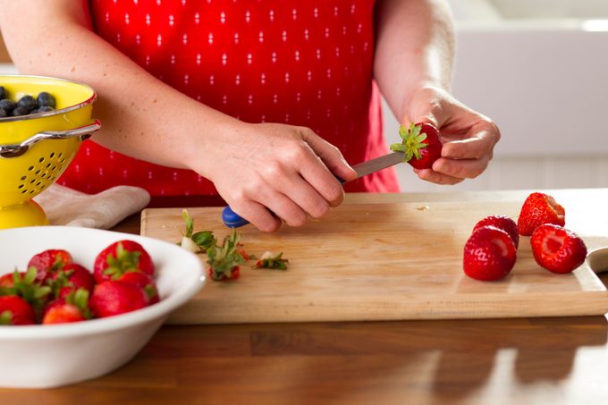 Person using a knife to remove the middle of a strawberry