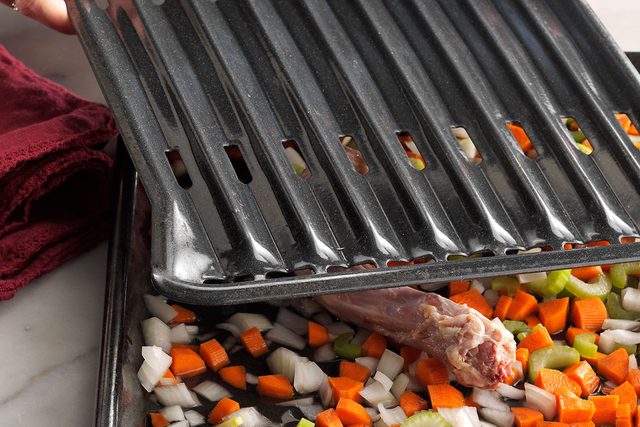 Turkey and diced vegetables on and inside a roasting pan