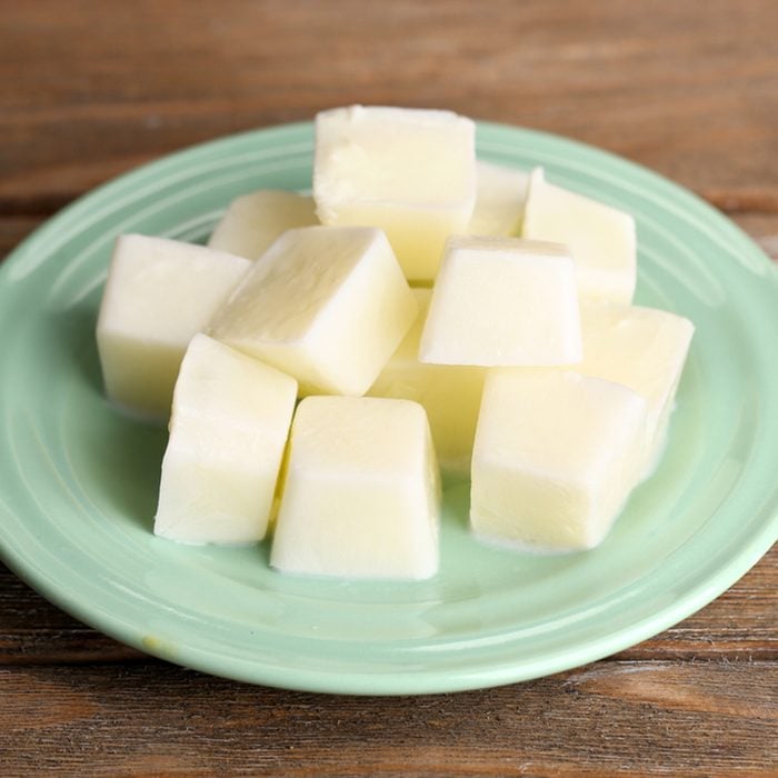 Milk ice cubes on plate on wooden background; Shutterstock ID 221290927