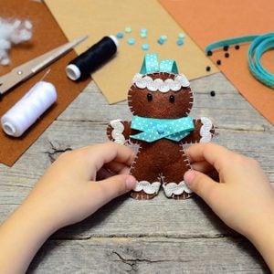 Child holding a felt gingerbread man in his hands.