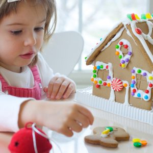 Little girl decorating gingerbread house for Christmas