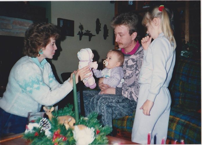 Mother, father and older sister presenting the family baby with a toy baby