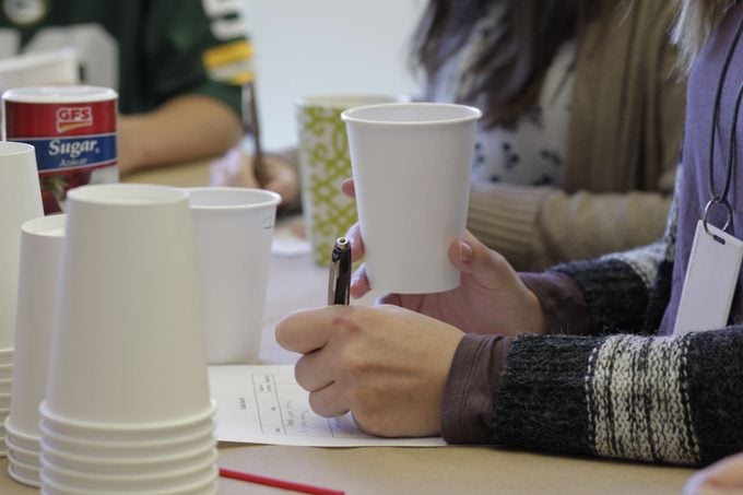 Person holding a cup of coffee as they take notes