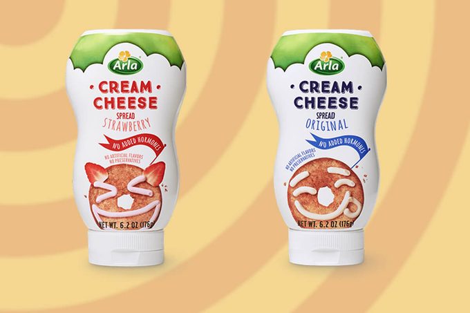 Two bottles of squeezable cream cheese against an orange and yellow background